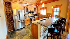 A spacious kitchen with wooden cabinets, a granite countertop, and a stone island. - Dreamcatcher Mountain Cabin - Ski-Bike-Golf-Relax (Kimberley)