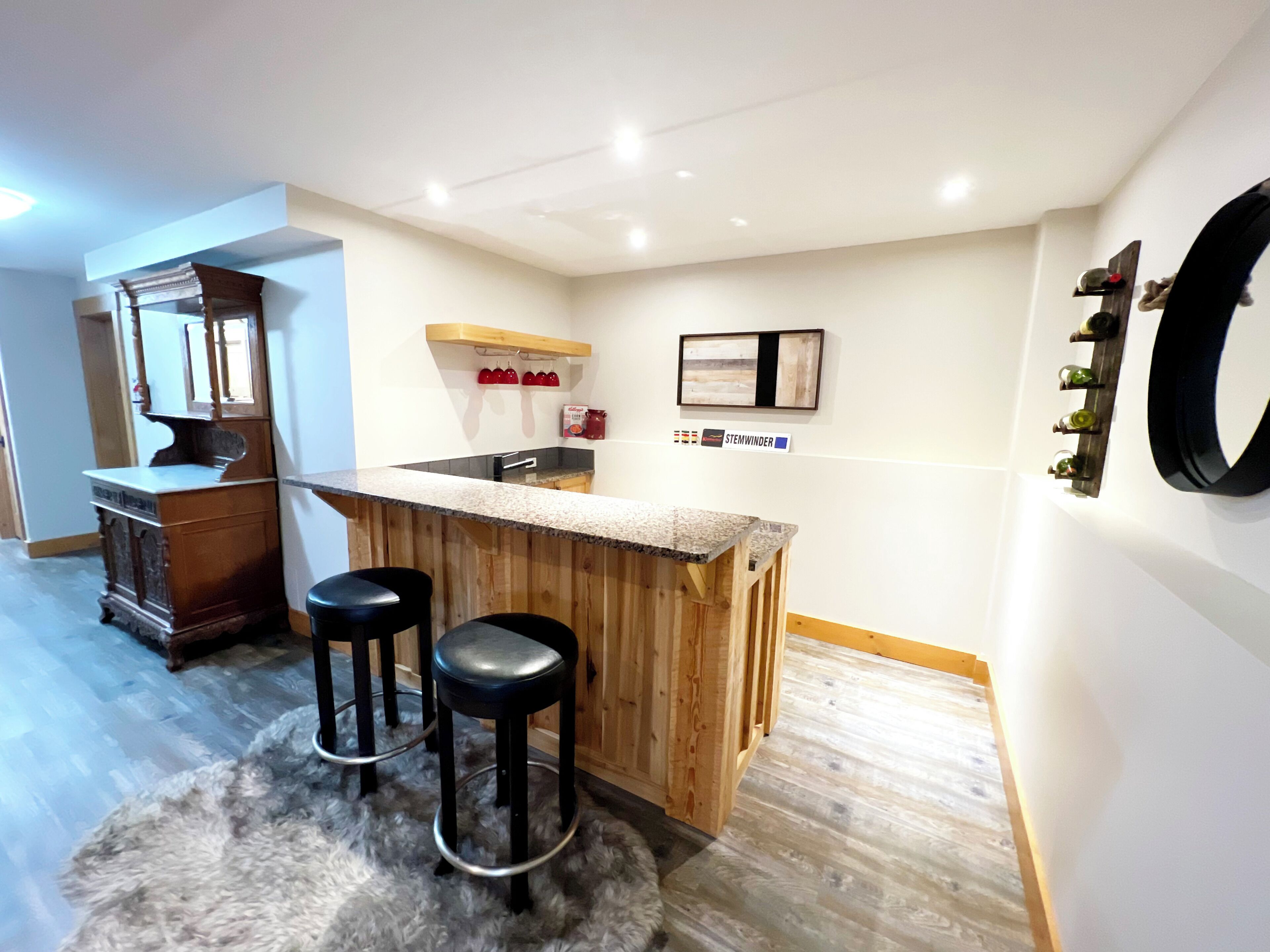 A compact kitchen with a wooden bar, two stools, and a refrigerator.