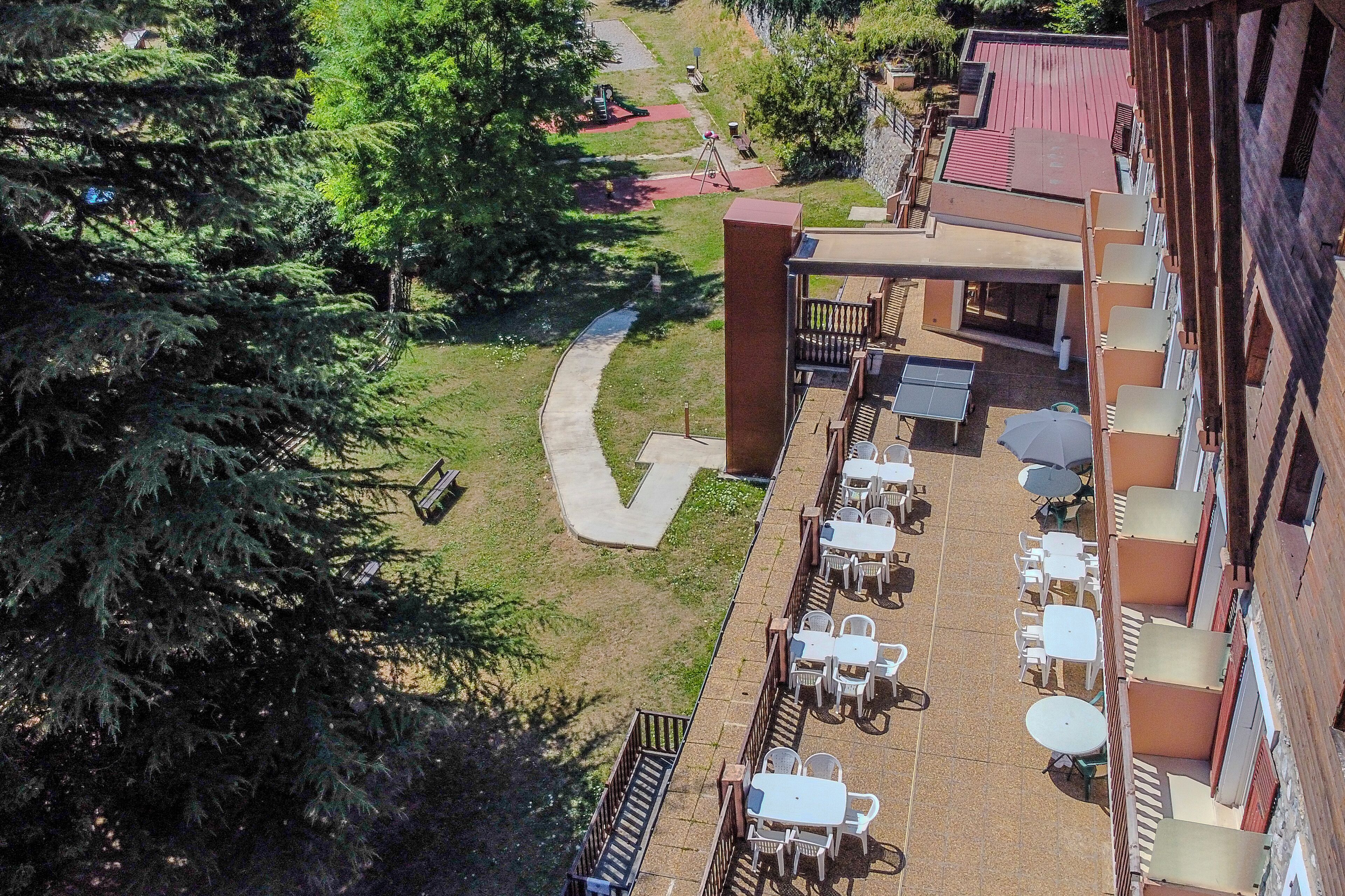 Un patio al aire libre con mesas y sillas, un camino y un edificio con balcones.