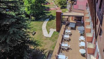Un patio al aire libre con mesas y sillas, un camino y un edificio con balcones.