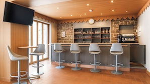 Una zona de bar con pared de piedra, techo de madera y televisor de pantalla plana.