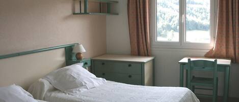 Une chambre avec deux lits simples, un bureau et une chaise.