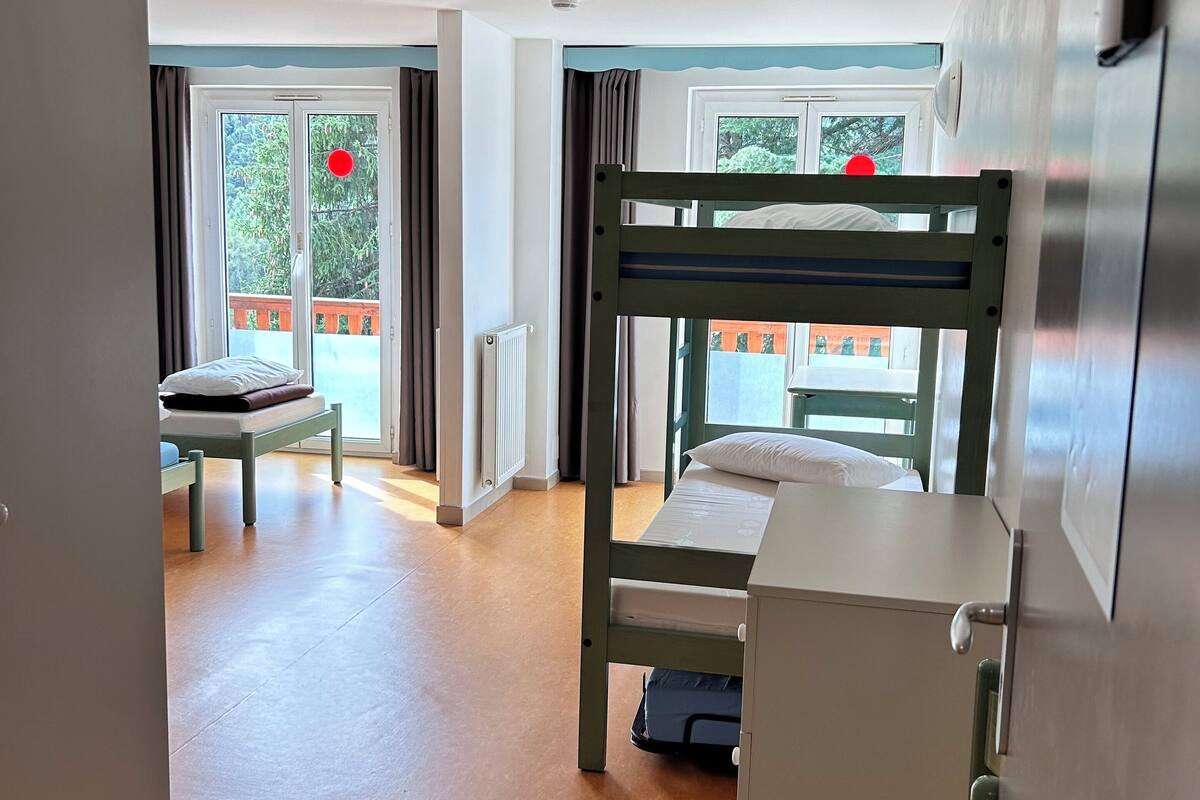 A room with bunk beds, a desk, and a chair.