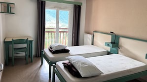 Una habitación con dos camas, un escritorio y una ventana con cortinas.