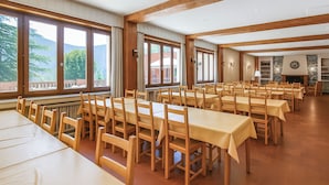 Un amplio comedor con mesas y sillas largas, ventanas grandes y una chimenea.