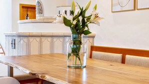 A wooden dining table with white chairs, a vase with flowers, and a chandelier with multiple bulbs. - NEW: Exclusive vacation home at Lechsee in the Allgäu (Lechbruck am See)