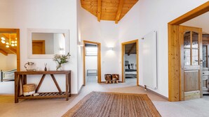A spacious room with a wooden ceiling, a large mirror, a console table with decorative items, and a view into another room through an open door. - NEW: Exclusive vacation home at Lechsee in the Allgäu (Lechbruck am See)