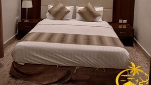 Una habitación de hotel moderna con una cama grande, dos mesitas de noche, una lámpara de techo y un cabecero de madera.