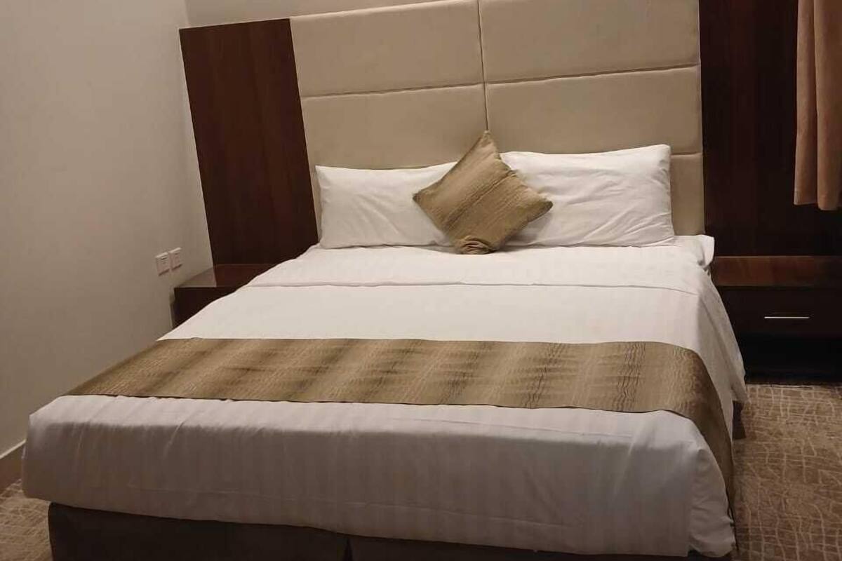 Una cama bien hecha con una colcha a rayas, un solo almohadón y un cabecero.