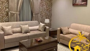 Una sala de estar con dos sofás color beige, una mesa de centro y una lámpara.