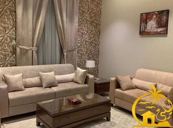 Una sala de estar con dos sofás color beige, una mesa de centro y una lámpara.