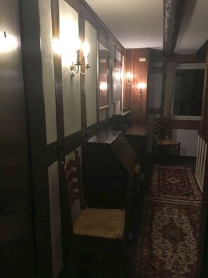 Classic dining room with a long table set for four, featuring a large mirror and comfortable seating.