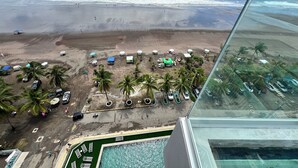 An aerial view of a beach with umbrellas, palm trees, and a pool.