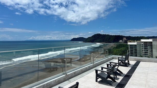 A rooftop terrace with a view of the ocean and a distant mountain.