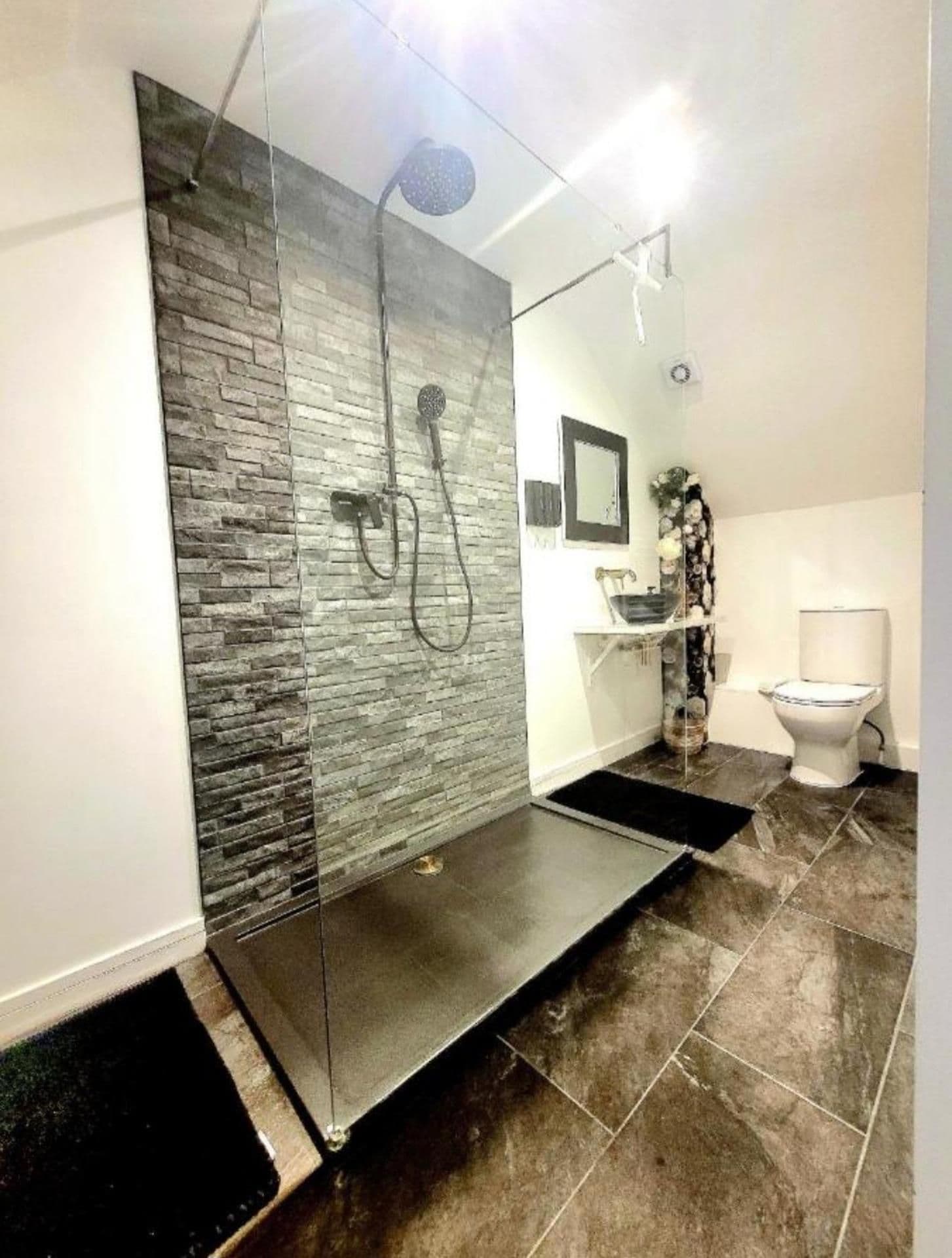 A modern bathroom with a glass shower enclosure, a toilet, and a sink.