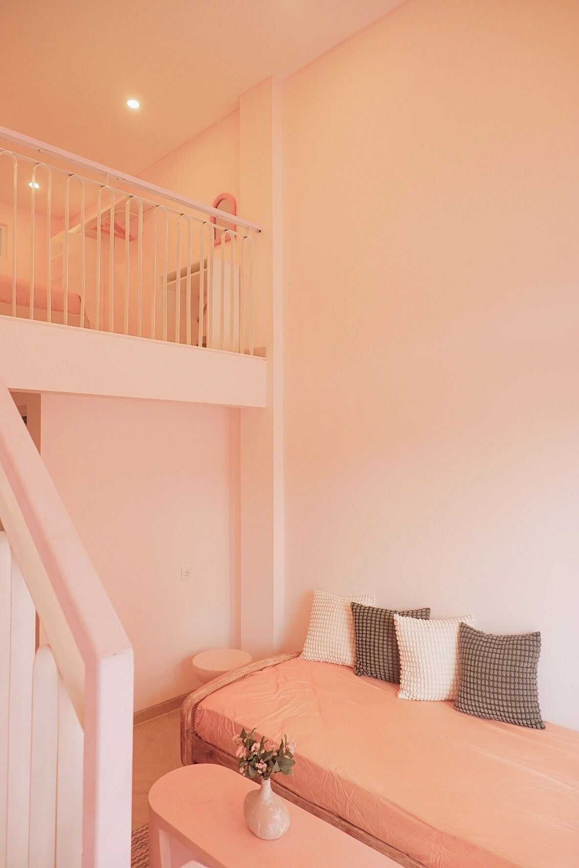 A bedroom with a bunk bed, a small table with a vase, and a staircase.