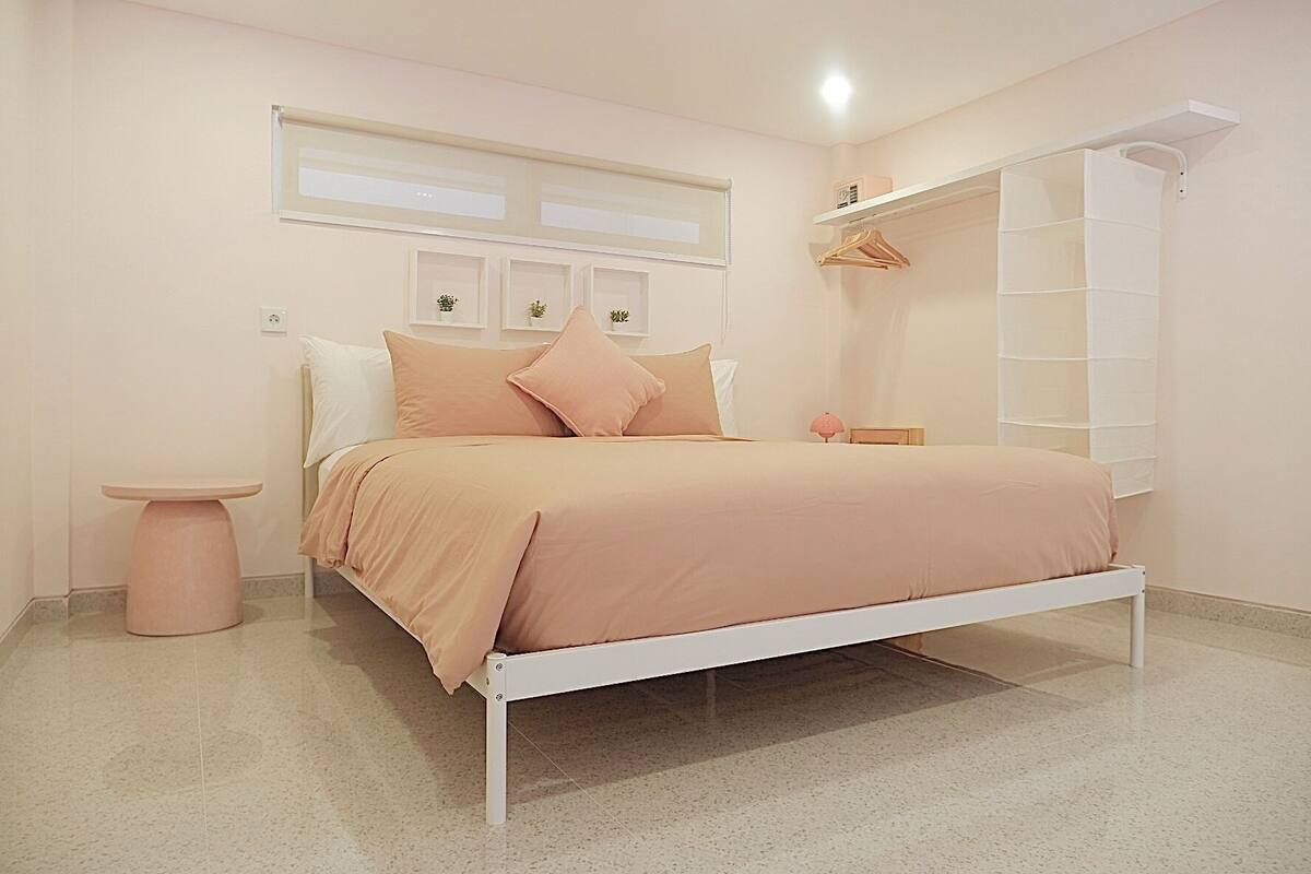 A bedroom with a bed, bedside table, and a small shelf with a lamp.