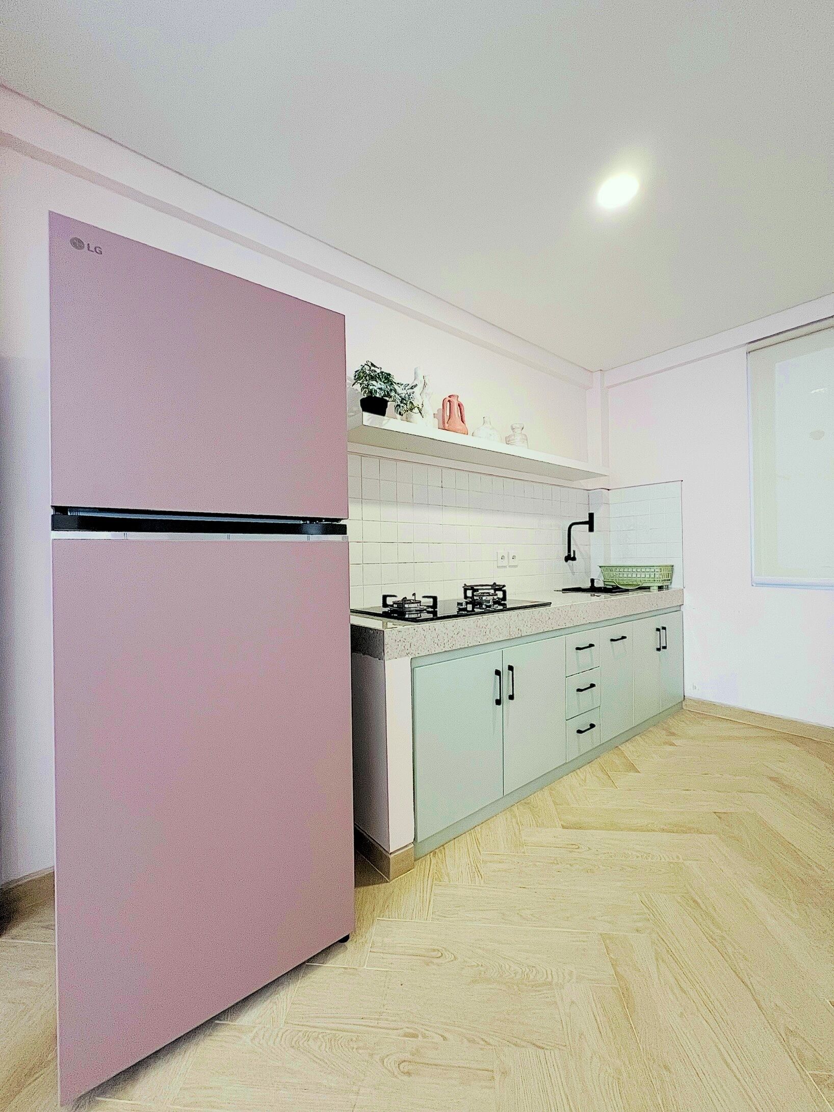 A kitchen with a pink refrigerator, a gas stove, and light-colored cabinets.