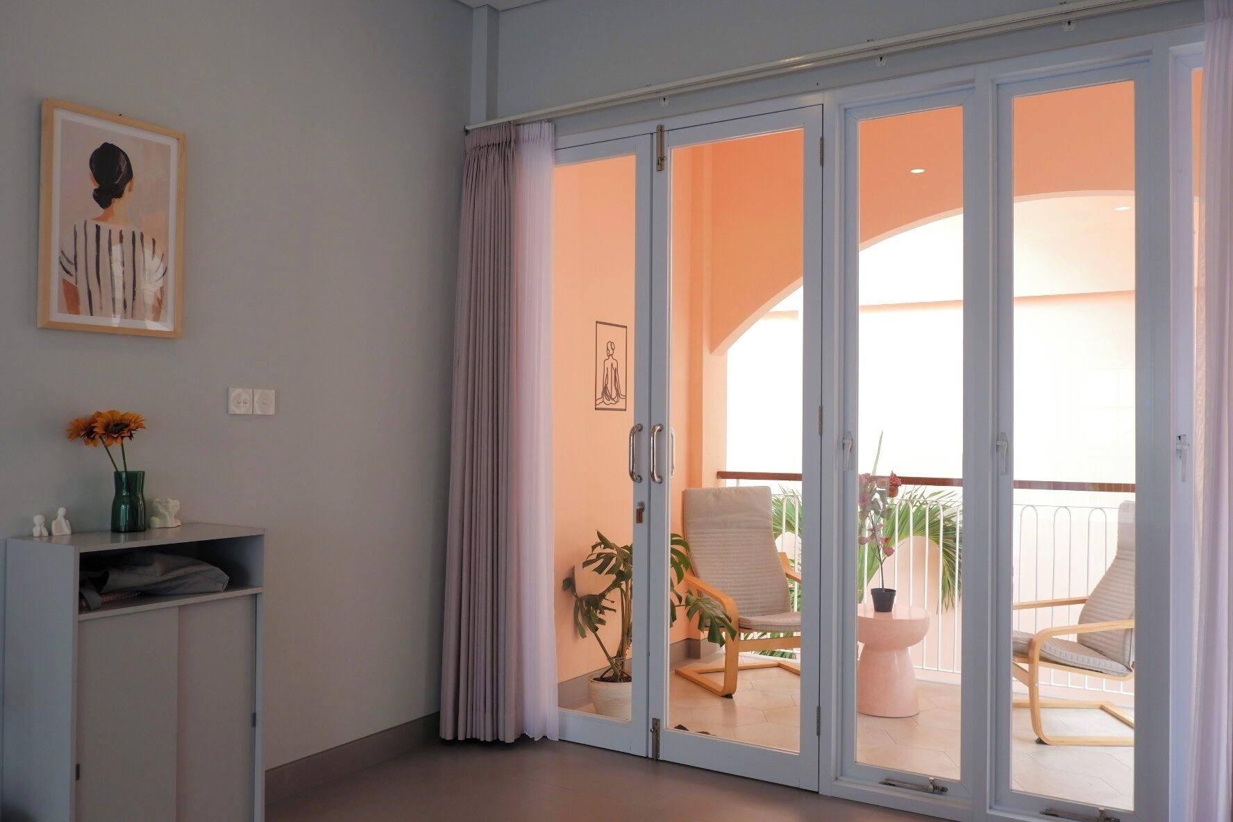 Une pièce dotée d’une porte-fenêtre coulissante donnant sur un balcon aménagé avec du mobilier d’extérieur et des plantes.