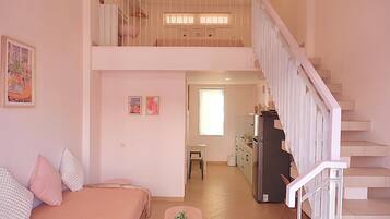 Un apartamento de dos pisos con balcón, kitchenette y comedor.