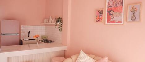 A modern kitchen with a pink theme, featuring a refrigerator, sink, and stove.