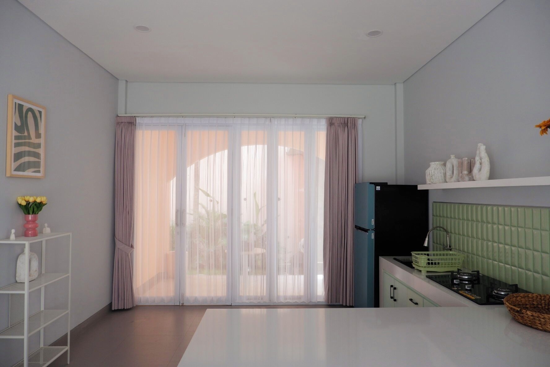 Una cocina moderna con un ventanal grande, un refrigerador y un salpicadero de azulejos verdes.