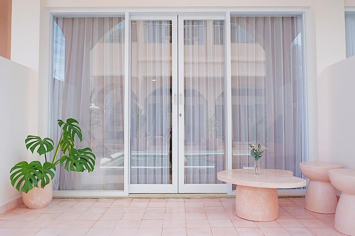 A modern patio with a sliding glass door, a round table, and two potted plants.