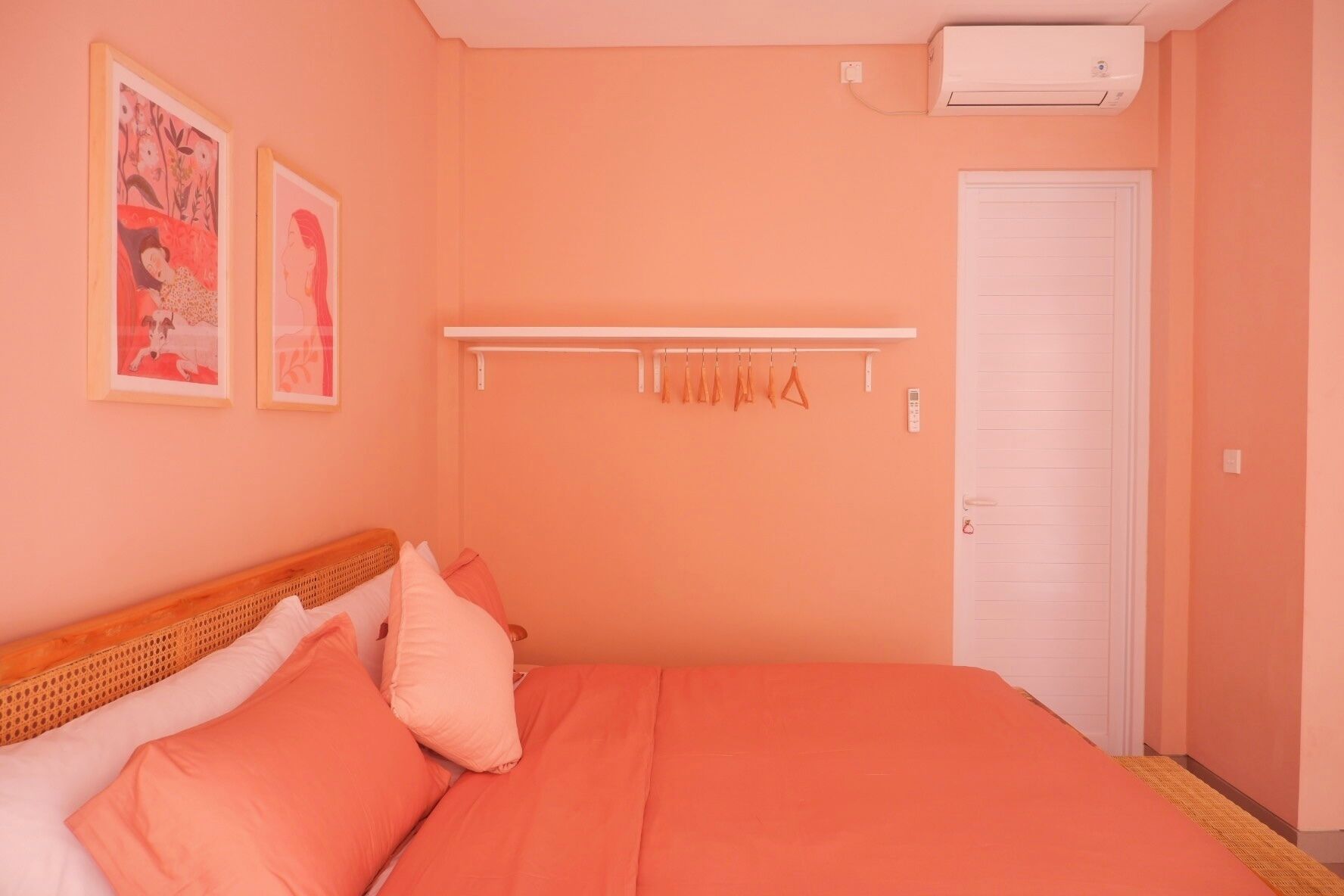 A bedroom with a bed, pillows, a white door, and a wall-mounted air conditioner.