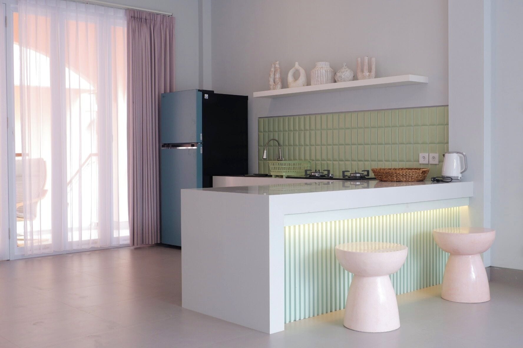 A modern kitchen with a central island, a refrigerator, and a green tiled backsplash.