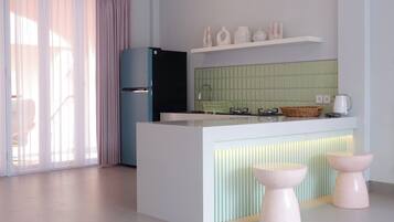 A modern kitchen with a central island, a refrigerator, and a green tiled backsplash.