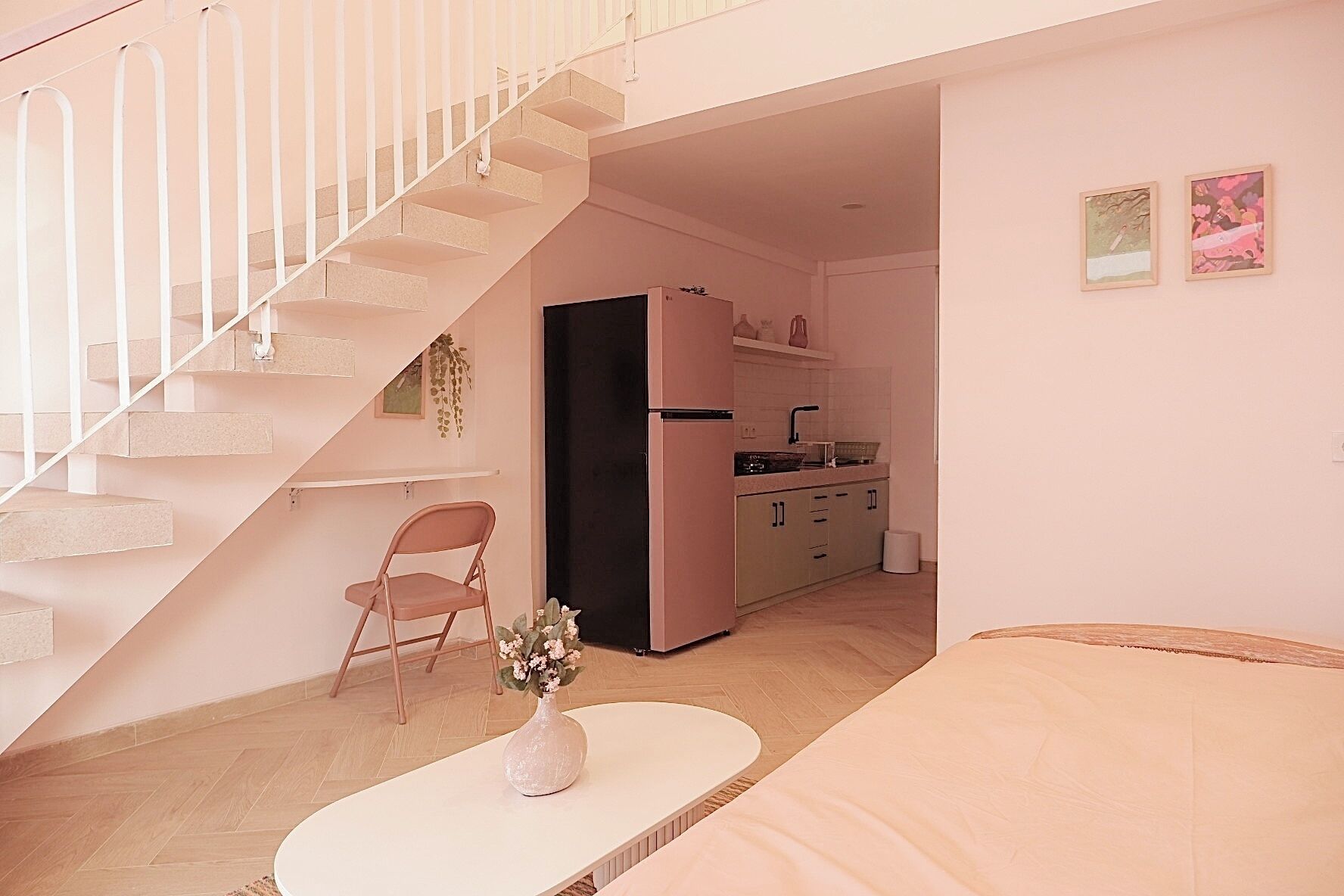 Ett kompakt bostadsutrymme med en trappa, ett litet kök och en matplats.