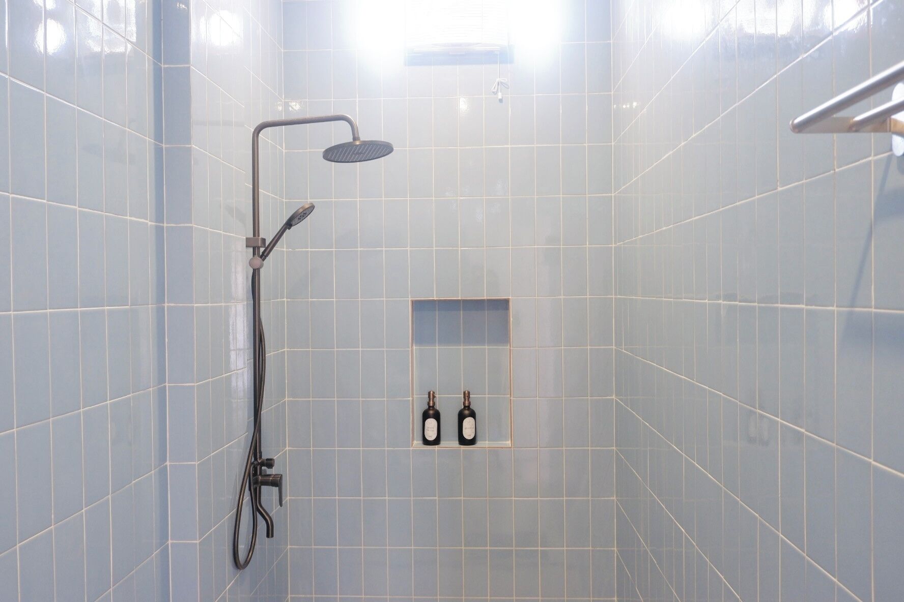 Douchegedeelte met betegelde wanden en een handdouche.