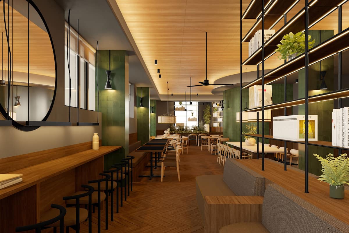 A modern restaurant interior with wooden floors, high tables, and chairs. There are shelves with books and plants, and a large mirror on the wall.