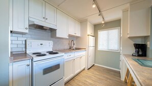 A modern kitchen with white cabinets, a white stove, and a refrigerator.