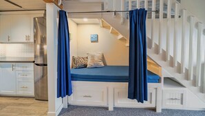 Une chambre avec un lit superposé, un escalier et un coin cuisine.