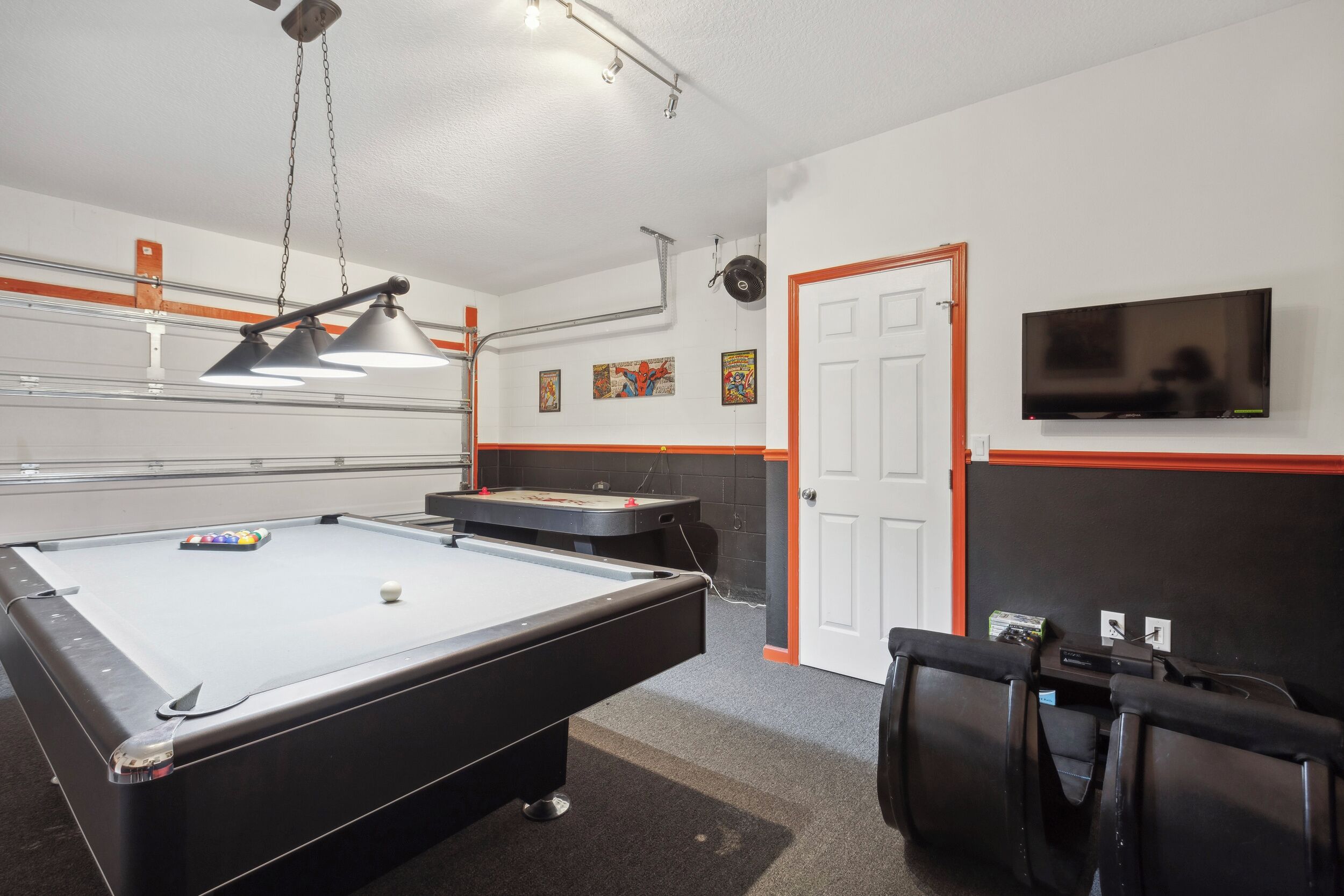 Une table de billard avec un jeu de billard, une table de billard et un téléviseur fixé au mur.