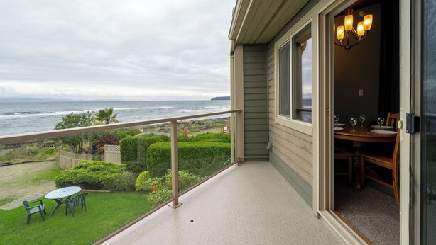 A balcony with a view of the ocean, a dining area with a table and chairs, and a chandelier. - #222 Upper Beach View Suite at Shorewater Resort, Qualicum Beach (Qualicum Beach)
