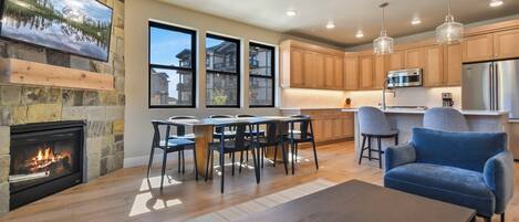 A modern living room with a fireplace, dining area, and kitchen.