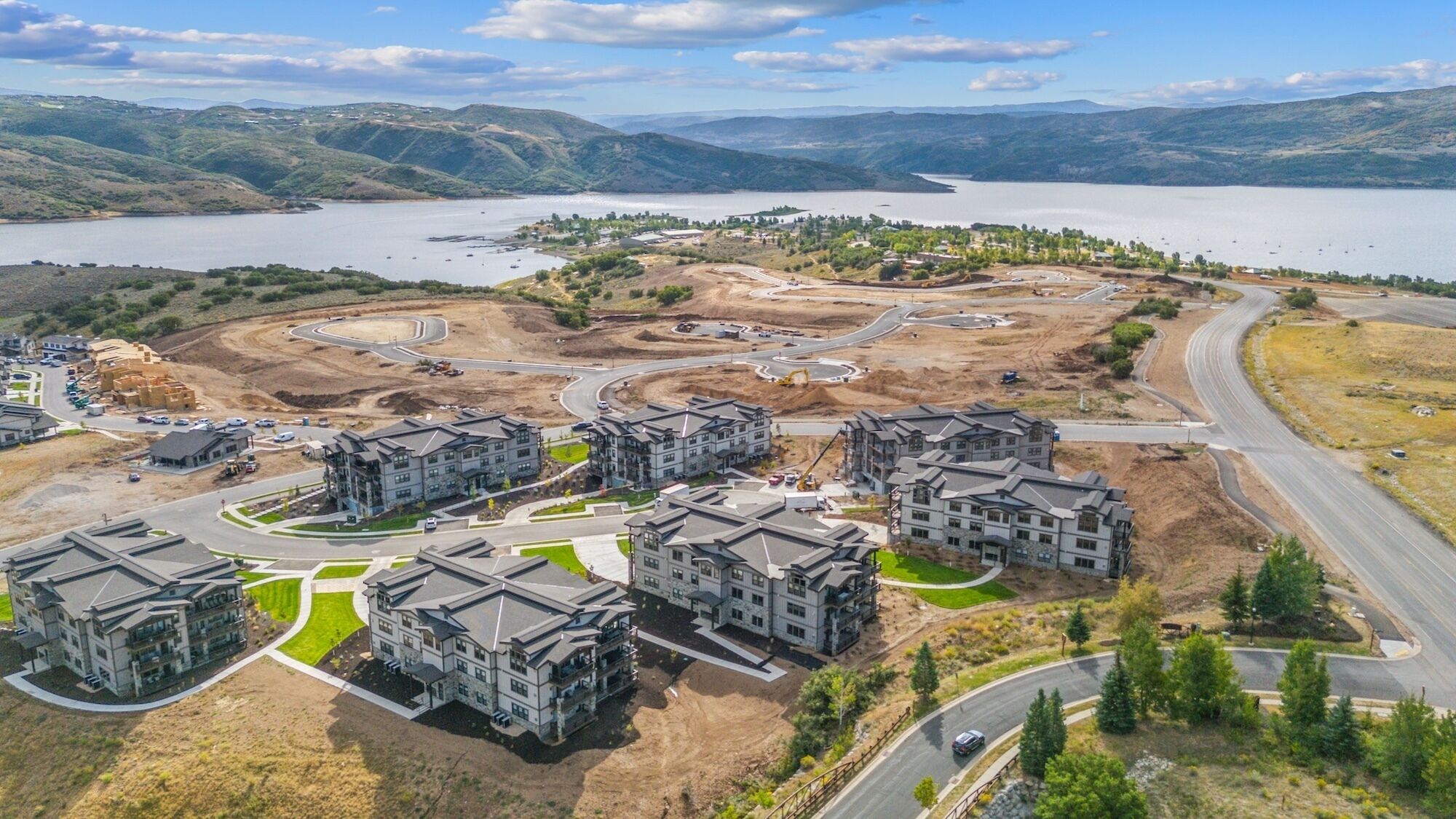 A residential area with multi-story buildings, roads, and a lake in the background.