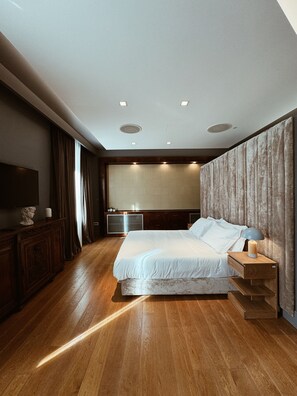 A modern hotel room with a large bed, wooden flooring, a flat-screen TV, and a wooden nightstand. - Residenza Imperiale - Luxury Guest House (Rome)