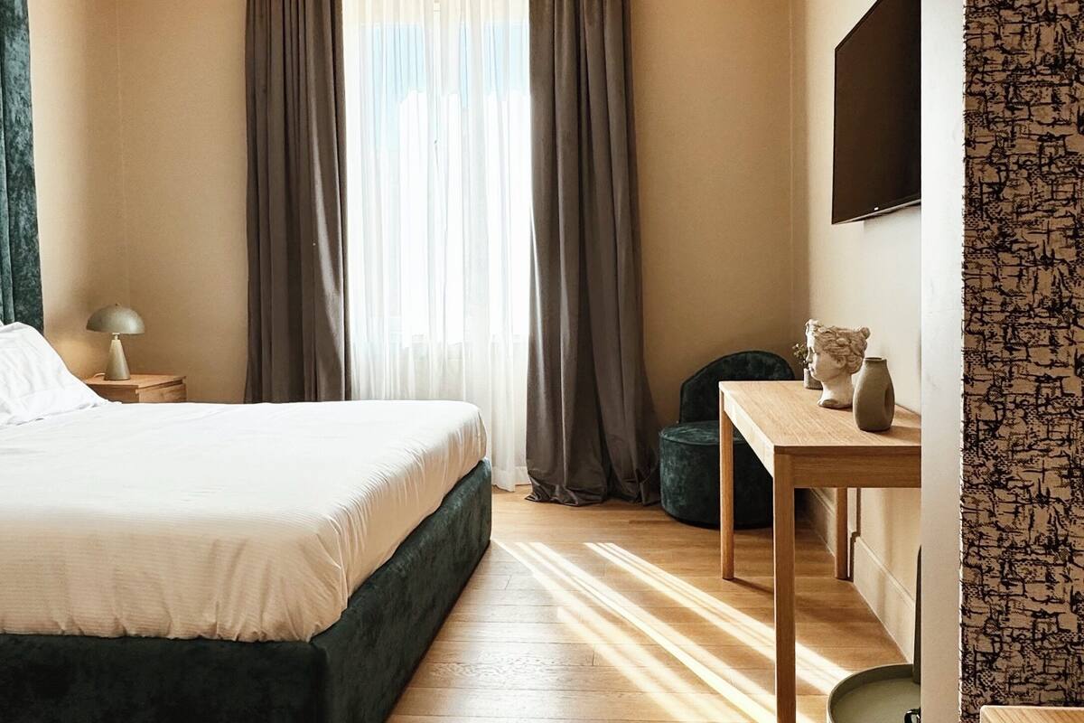 Una habitación de hotel moderna con una cama grande, un escritorio y un televisor en la pared.