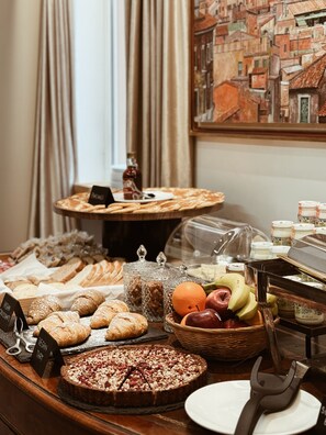 A buffet with various food items including pastries, fruits, and a cake. - Residenza Imperiale - Luxury Guest House (Rome)