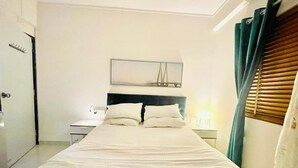 Une chambre d’hôtel avec un lit, une table de chevet, un miroir et une fenêtre avec des rideaux.