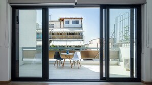 Habitación con puerta corrediza de vidrio que da a un balcón exterior con dos sillas y una mesa.