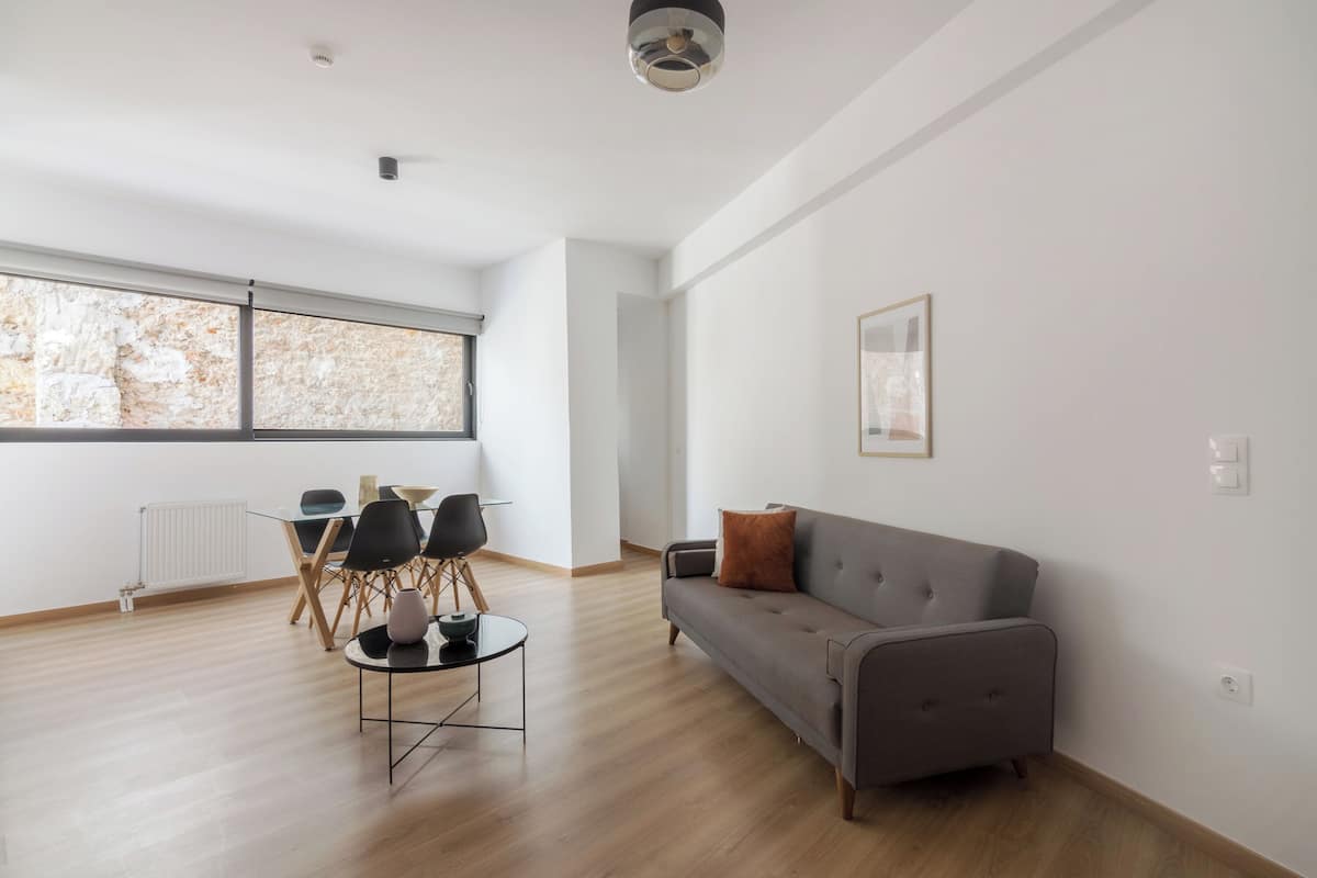 Een moderne woonkamer met een grijze bank, een salontafel en een eethoek met stoelen en een tafel.