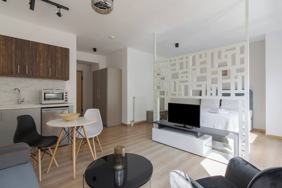 Een moderne woonruimte met een keuken, een eethoek en een tv-meubel.