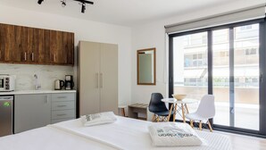 Una habitación de hotel con cama, una kitchenette pequeña, una zona de comedor y un balcón con vistas.