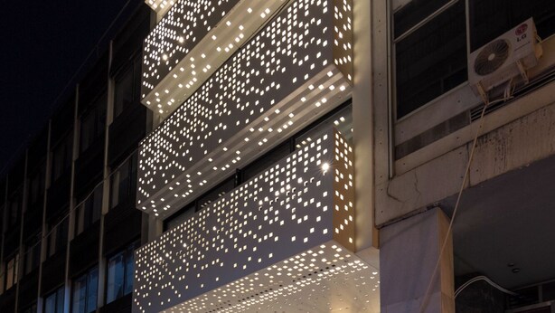 Un edificio con fachada moderna y una serie de paneles iluminados.