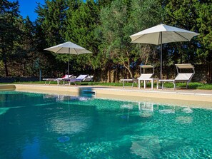 A clear swimming pool with lounge chairs and umbrellas.