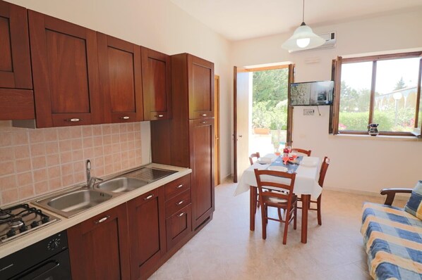 A compact kitchen with wooden cabinets, a sink, and a dining area with a table and chairs.